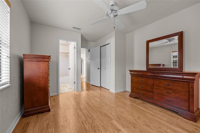 bedroom with visible vents, baseboards, light wood-style floors, a closet, and ensuite bath