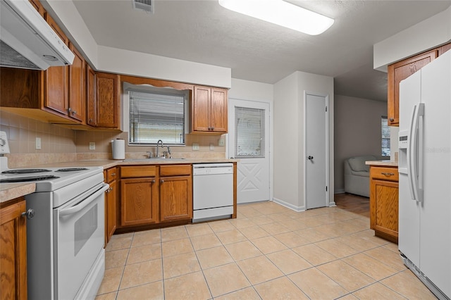 kitchen with white appliances, a sink, light countertops, ventilation hood, and brown cabinetry