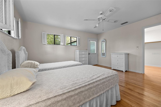 bedroom with a ceiling fan, baseboards, visible vents, and wood finished floors