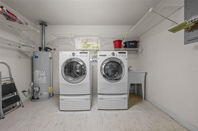 washroom featuring laundry area, baseboards, gas water heater, and washing machine and clothes dryer