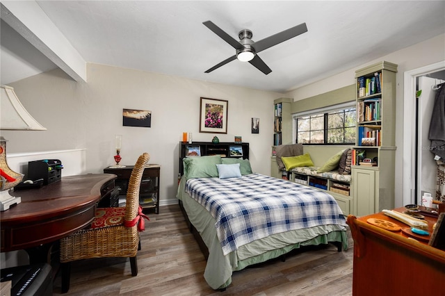 bedroom with beam ceiling, wood finished floors, and a ceiling fan