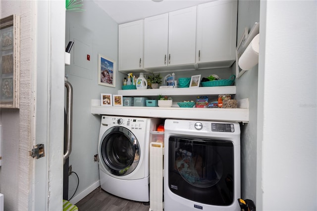 laundry area featuring wood finished floors, washing machine and clothes dryer, cabinet space, and baseboards