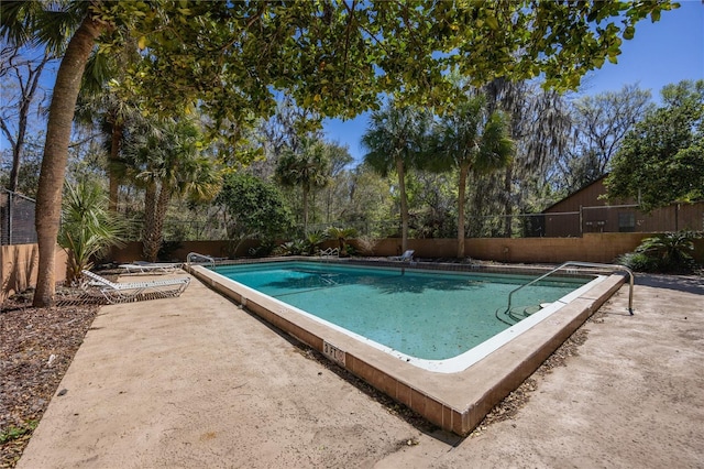 pool with a patio area and fence