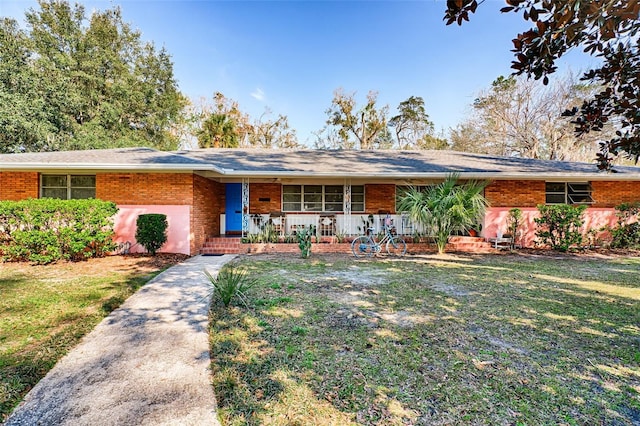 ranch-style house featuring a porch, a front yard, and brick siding