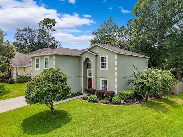 traditional home with a front yard, fence, and stucco siding