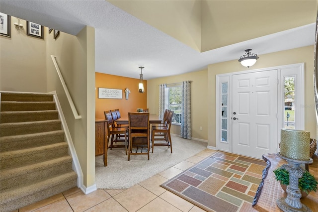 foyer featuring light tile patterned floors, stairway, light carpet, and baseboards