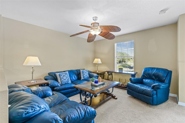 living area with a textured ceiling, carpet floors, a ceiling fan, and baseboards