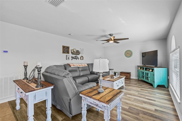 living area with light wood-style floors, visible vents, and ceiling fan