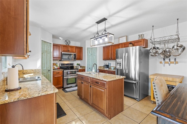 kitchen featuring stainless steel appliances, a sink, a center island with sink, and light stone countertops