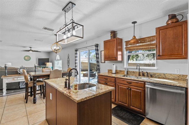 kitchen with a sink, visible vents, open floor plan, stainless steel dishwasher, and light stone countertops