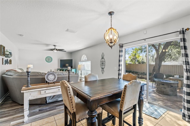 dining room featuring visible vents, light tile patterned flooring, a textured ceiling, and ceiling fan with notable chandelier