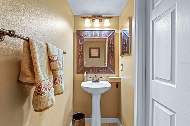 bathroom featuring a textured ceiling and baseboards