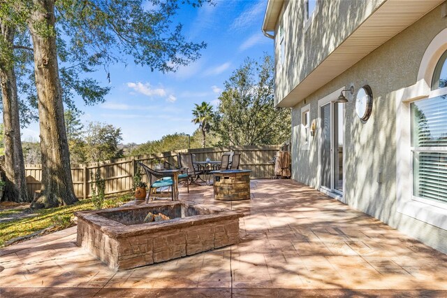 view of patio featuring an outdoor fire pit and fence