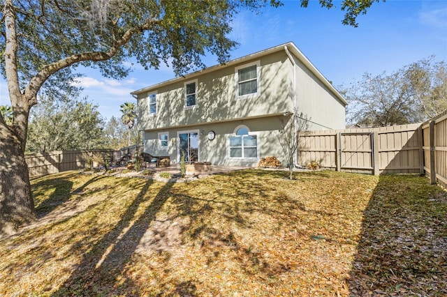 rear view of house with a fenced backyard, a patio, and stucco siding