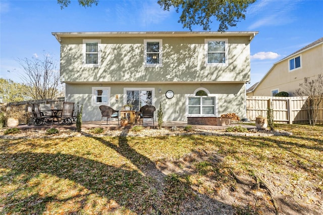 rear view of property featuring a patio area, fence, and stucco siding