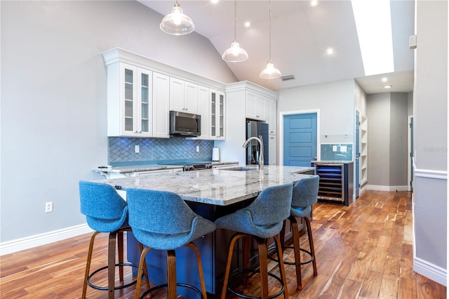 kitchen featuring light wood-style floors, appliances with stainless steel finishes, white cabinets, and backsplash