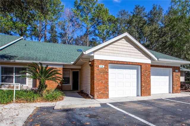 single story home featuring brick siding, driveway, an attached garage, and roof with shingles