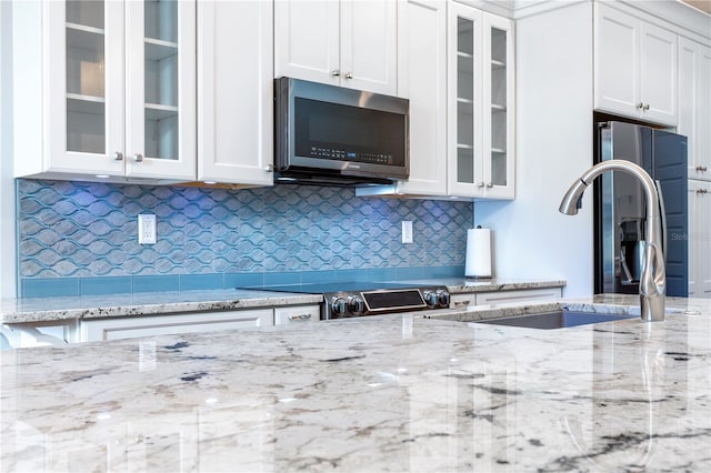 kitchen featuring white cabinets, electric range oven, glass insert cabinets, stainless steel microwave, and a sink