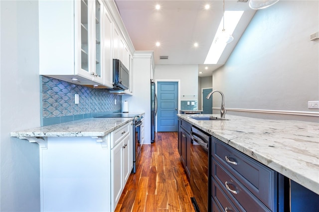 kitchen featuring light stone counters, appliances with stainless steel finishes, glass insert cabinets, white cabinetry, and a sink