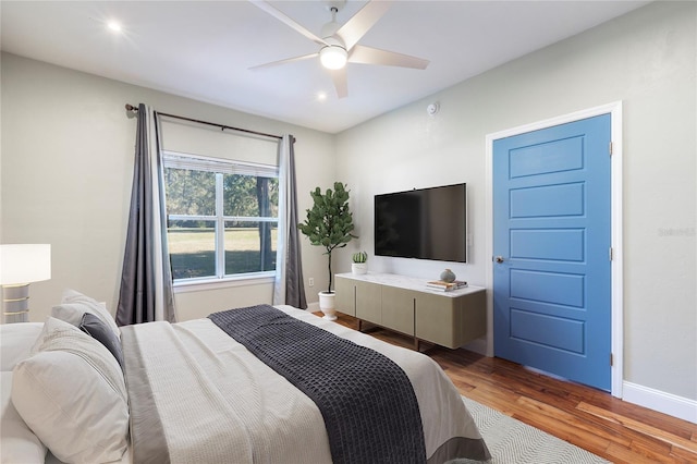 bedroom with ceiling fan, wood finished floors, and baseboards