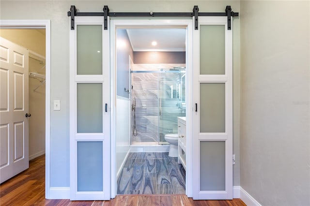 bathroom with a stall shower, baseboards, toilet, and wood finished floors