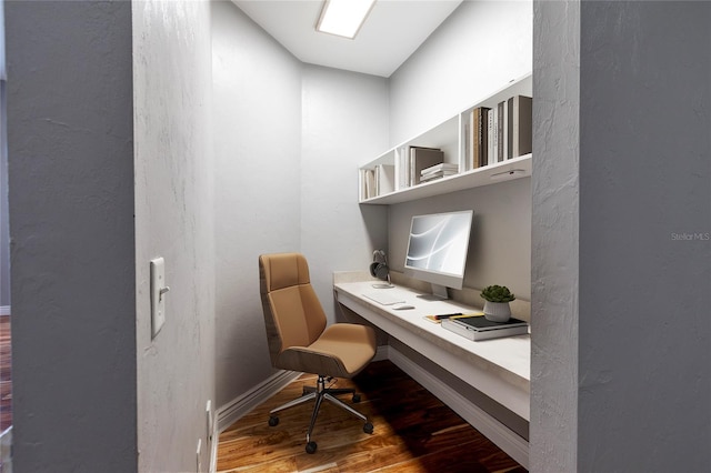 office space with baseboards, built in desk, and wood finished floors