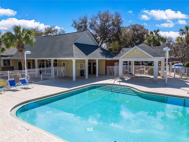 community pool with a patio area and fence