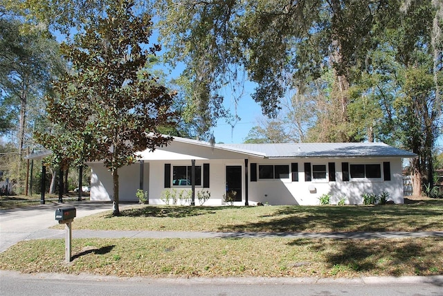 ranch-style home with a front yard, stucco siding, a carport, and aphalt driveway