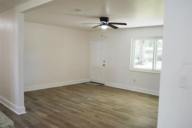 empty room with visible vents, baseboards, dark wood-style flooring, and ceiling fan