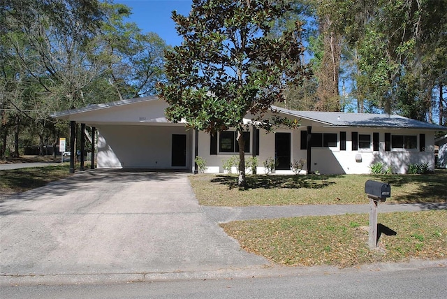 ranch-style house with concrete driveway, a front lawn, and stucco siding