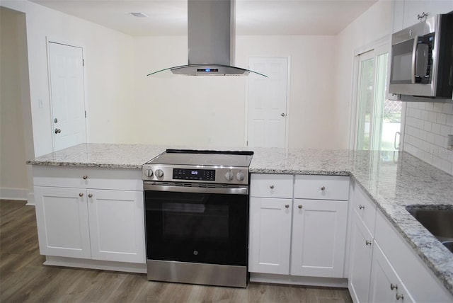 kitchen with white cabinets, light wood-style floors, appliances with stainless steel finishes, and island range hood