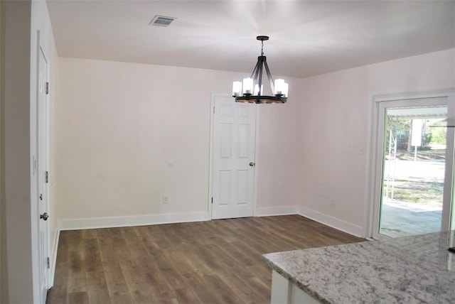 unfurnished dining area with visible vents, baseboards, an inviting chandelier, and wood finished floors