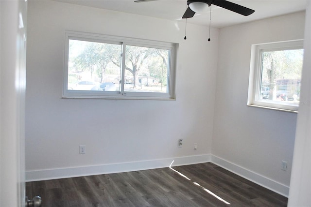 empty room featuring a wealth of natural light, dark wood-style floors, a ceiling fan, and baseboards