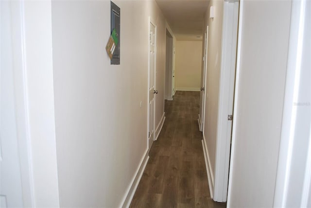 corridor featuring dark wood-type flooring and baseboards