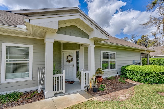 view of exterior entry with covered porch and roof with shingles