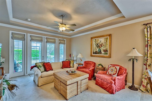 living room with light colored carpet, a ceiling fan, ornamental molding, french doors, and a tray ceiling