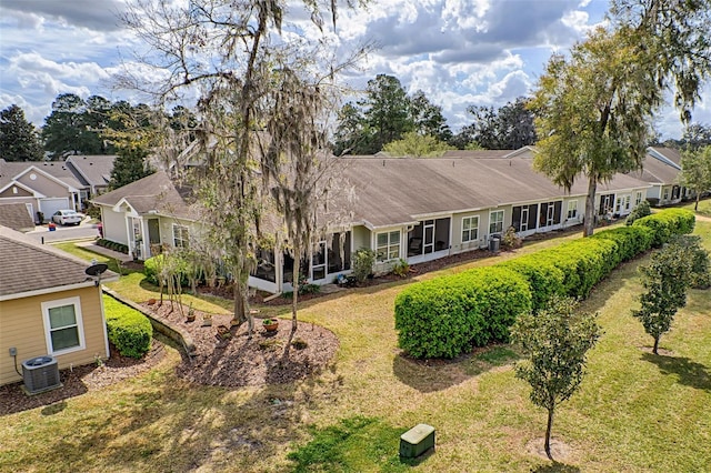 view of front of house with central air condition unit, a sunroom, and a front yard