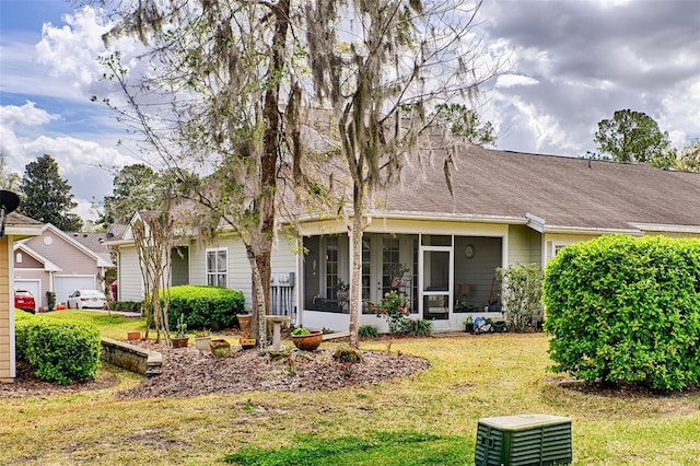 rear view of house featuring a sunroom, roof with shingles, and a yard