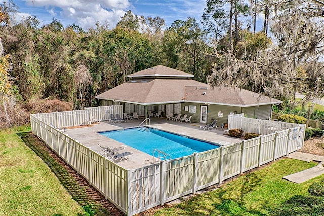 community pool with a patio area, a fenced backyard, and a lawn