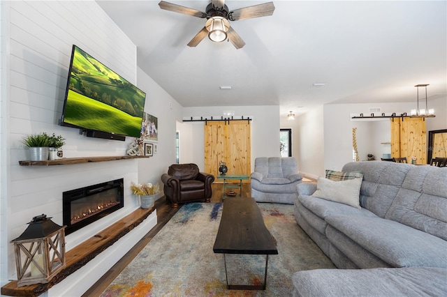 living area with a ceiling fan, a glass covered fireplace, wood finished floors, and a barn door