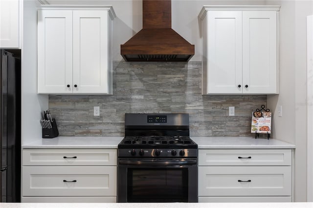 kitchen featuring gas range, custom exhaust hood, light countertops, and freestanding refrigerator