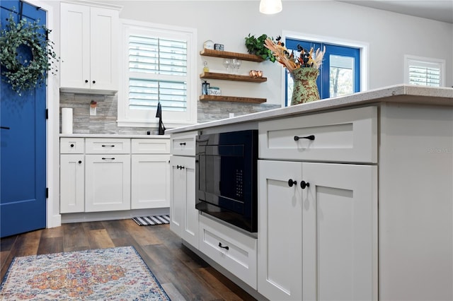 kitchen featuring white cabinetry, black microwave, light countertops, and dark wood-style flooring