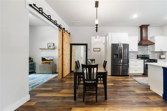 dining room with dark wood-type flooring, recessed lighting, and a barn door