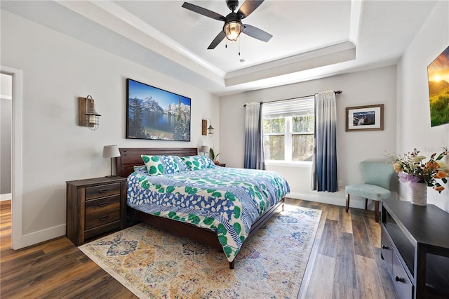 bedroom featuring dark wood-style floors, ceiling fan, a tray ceiling, and baseboards