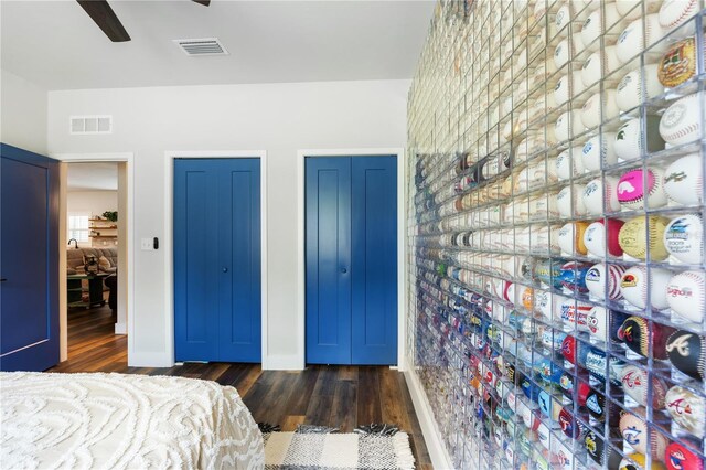 bedroom with two closets, dark wood finished floors, and visible vents