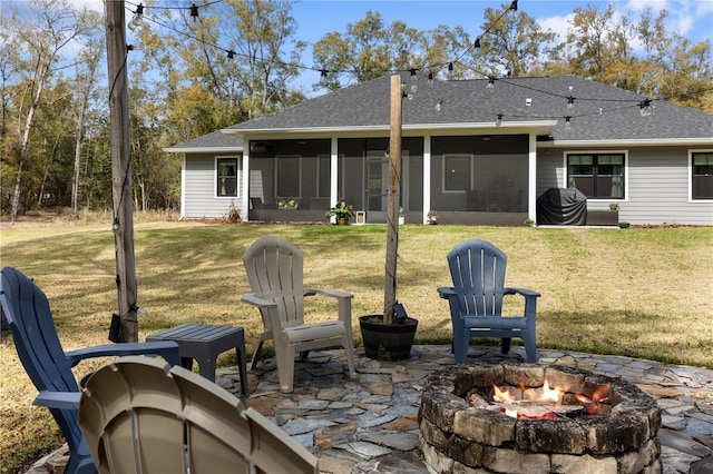 rear view of property with a patio area, a lawn, a fire pit, and a sunroom