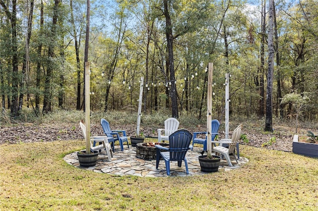 view of yard with an outdoor fire pit, a patio area, and a view of trees