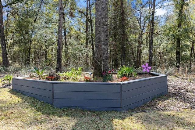 view of swimming pool featuring a vegetable garden and a wooded view