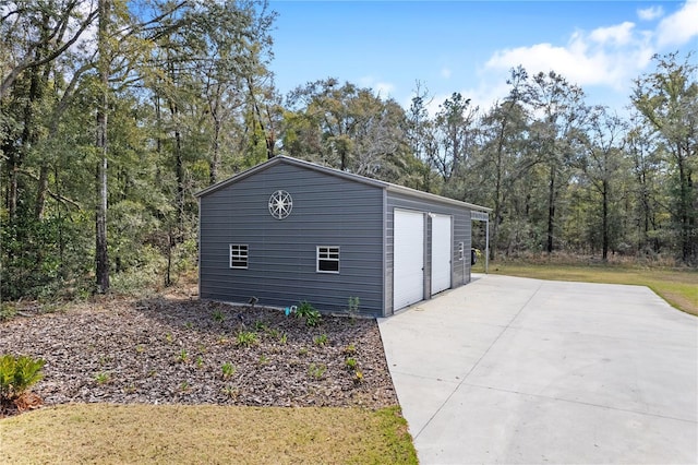 detached garage with a view of trees