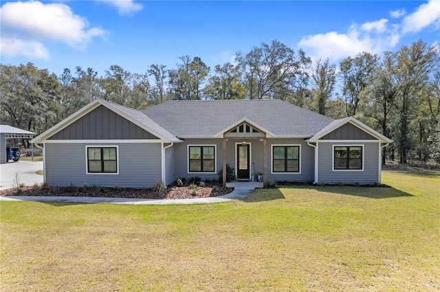 view of front of house with board and batten siding, a shingled roof, and a front lawn